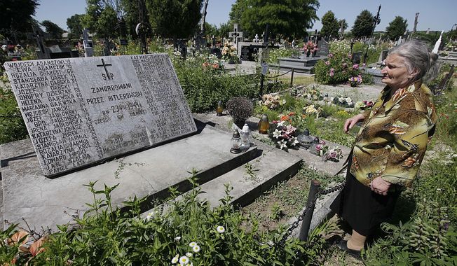 A woman stands near a mass grave and a monument in the village of Chlaniow, Poland, on June 19, 2013 that holds the bodies of Poles killed in a 1944 attack on the village by the Nazi SS-led Ukrainian Self Defense Legion. Officials in Poland and Ukraine, staunch strategic partners, have unexpectedly exchanged bitter remarks regarding a painful mutual past that includes mass murder. Seeking to calm emotions, an aide to Poland’s President Andrzej Duda said Monday May 22, 2023 that the Poles only wanted the truth and respect for the tens of thousands of Polish victims. (AP Photo/Czarek Sokolowski) **FILE**