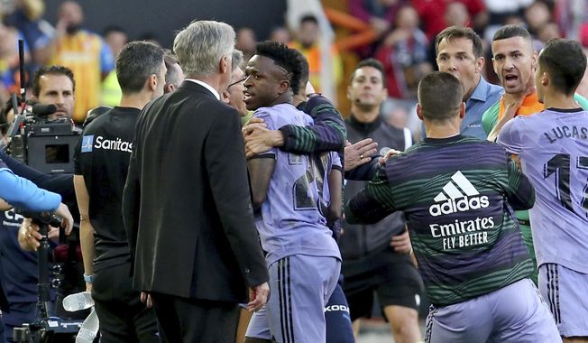 Real Madrid&#x27;s Vinicius Junior, centre, walks past head coach Carlo Ancelotti, front left, after being sent off the pitch during a Spanish La Liga soccer match between Valencia and Real Madrid, at the Mestalla stadium in Valencia, Spain, Sunday, May 21, 2023. The game was temporarily stopped when Vinicius said a fan had insulted him from the stands. He was later sent off after clashing with Valencia players. (AP Photo/Alberto Saiz)