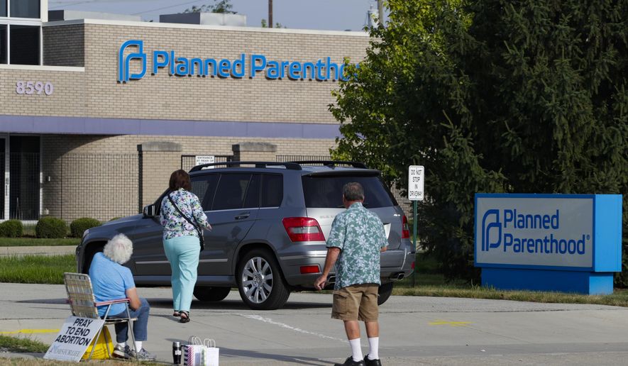 Abortion protesters attempt to hand out literature at a Planned Parenthood clinic in Indianapolis, on Aug. 16, 2019. Planned Parenthood is shifting funding to its state affiliates and cutting national office staff to reflect a changed landscape in both how abortion is provided and how battles over access are playing out. The group, a major provider of abortion and other health services and also an advocate for abortion access, told its staff on Monday, May 22, 2023, that layoff notices would go out in June and provided The Associated Press with an overview Tuesday. (AP Photo/Michael Conroy, File)