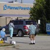 Abortion protesters attempt to hand out literature at a Planned Parenthood clinic in Indianapolis, on Aug. 16, 2019. Planned Parenthood is shifting funding to its state affiliates and cutting national office staff to reflect a changed landscape in both how abortion is provided and how battles over access are playing out. The group, a major provider of abortion and other health services and also an advocate for abortion access, told its staff on Monday, May 22, 2023, that layoff notices would go out in June and provided The Associated Press with an overview Tuesday. (AP Photo/Michael Conroy, File)