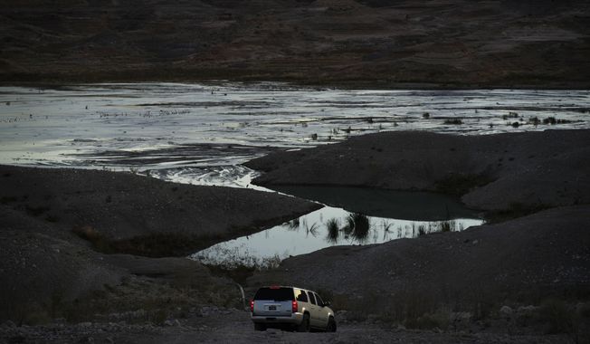 A car drives along a dirt road near Lake Mead at the Lake Mead National Recreation Area on Jan. 27, 2023, near Boulder City, Nev. Arizona, California and Nevada said on Monday, May 23, 2023, that they have reached an agreement to cut their use of the Colorado River in exchange for federal money. (AP Photo/John Locher, File)