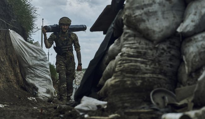 A Ukrainian soldier carries supplies in a trench at the frontline near Bakhmut in the Donetsk region, Ukraine, Monday, May 22, 2023. (AP Photo/Libkos)