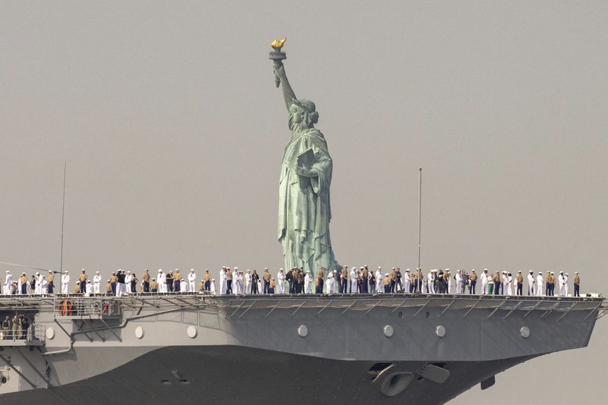 U.S. Sailors and Marines stand on the deck of the USS Wasp, an amphibious assault ship, as it passes the Statue of Liberty during Fleet Week on Wednesday, May 24, 2023 in New York. (AP Photo/Yuki Iwamura)