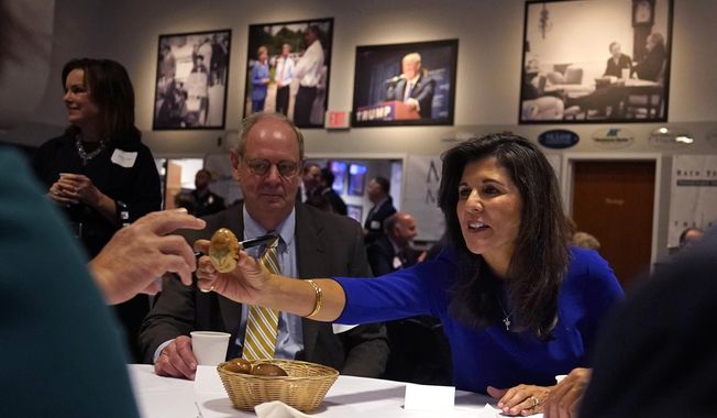 Republican presidential candidate Nikki Haley passes an autographed wooden egg to a guest during a breakfast gathering at Saint Anselm College, Wednesday, May 24, 2023, in Manchester, N.H. (AP Photo/Charles Krupa)