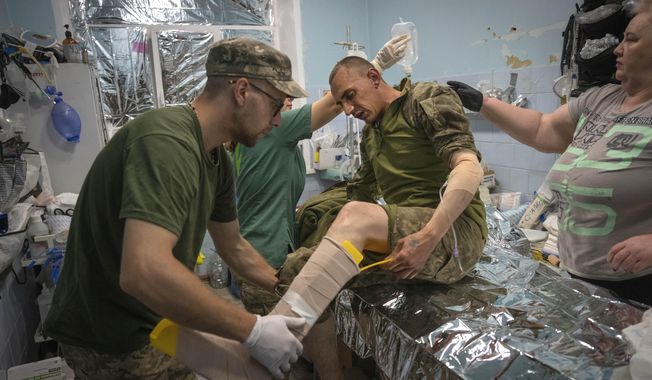 Military medics give first aid to wounded Ukrainian soldiers at a medical stabilisation point near Bakhmut, Donetsk region, Ukraine, Wednesday, May 24, 2023. (AP Photo/Efrem Lukatsky)