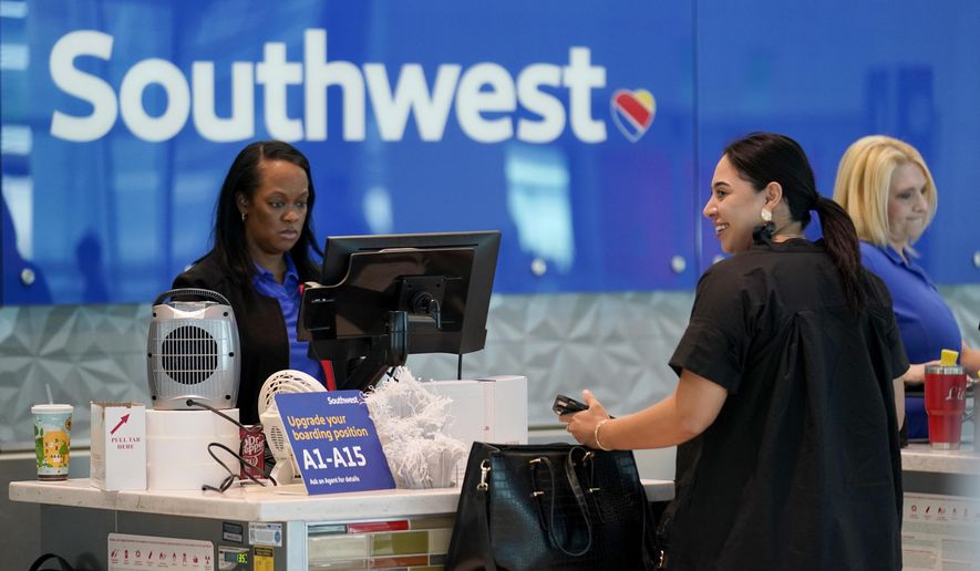A Southwest airlines customer service representative, left, assists a traveler at the ticketing counter at Love Field airport, Friday, May 19, 2023, in Dallas. The unofficial start of the summer travel season is here, with airlines hoping to avoid the chaos of last year and travelers scrounging for ways to save a few bucks on pricey airfares and hotel rooms.(AP Photo/Tony Gutierrez)