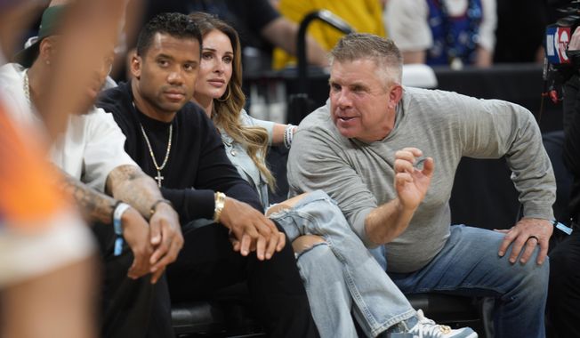 Denver Broncos head coach Sean Payton, right, chats with quarterback Russell Wilson, left, as Payton&#x27;s wife, Skylene, looks on from courtside seats in the first half of Game 5 of an NBA basketball semifinal playoff series between the Phoenix Suns and Denver Nuggets Tuesday, May 9, 2023, in Denver. (AP Photo/David Zalubowski)