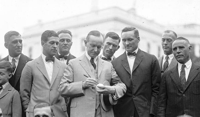 President Calvin Coolidge signs a baseball for Hall of Fame pitcher Walter Johnson as other members of the Senators look on in 1924. (Library of Congress via AP)