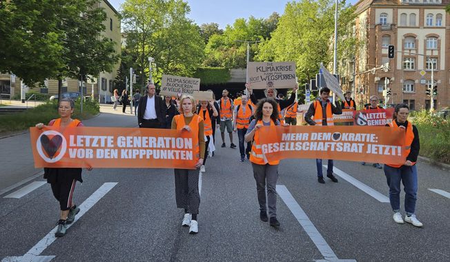 Activists and supporters of the group &#x27;Letzte Generation&#x27; Last Generation demonstrate in Stuttgart, Friday May 26, 2023. A German government spokesperson on Friday rejected the notion that comments by Chancellor Olaf Scholz criticizing climate activists might have prompted raids against them this week. (Andreas Rosar/dpa via AP)