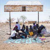 South Sudanese sit under the shade of a makeshift bus stop in Renk, South Sudan Wednesday, May 17, 2023. Tens of thousands of South Sudanese are flocking home from neighboring Sudan, which erupted in violence last month. (AP Photo/Sam Mednick)