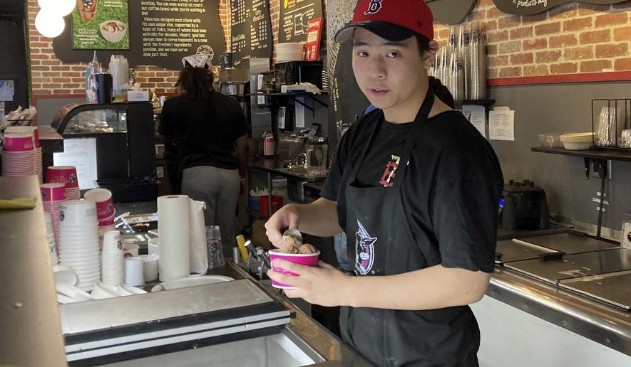 Christopher Au, 19, dishes out ice cream at a J.P. Licks in Boston’s Beacon Hill neighborhood on Thrusday, May 25, 2023. Au, who has worked at the shop for the past few months, said that having a job helps him be more independent and not to have to rely on his parents too much for spending money. Teens willing to work hold even more sway these days, thanks to one of the tightest job markets in decades. (AP Photo/Steve LeBlanc)