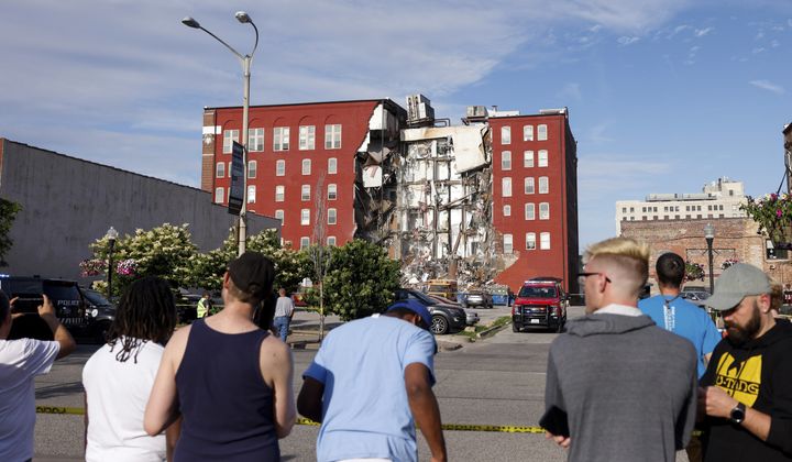 CORRECTS TO MAIN STREET INSTEAD OF WEST THIRD STREET-- Onlookers watch as emergency crews work the scene of a partial building collapse on the 300 block of Main Street, Sunday, May 28, 2023, in Davenport, Iowa. (Nikos Frazier/Quad City Times via AP)