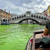 In this image released by the Italian firefighters, a firefighter on a boat looks at the arched Rialto Bridge along Venice&#x27;s historical Grand Canal as a patch of phosphorescent green liquid spreads in it, Sunday, May 28, 2023. Police in Venice are investigating the source of a phosphorescent green liquid patch that appeared Sunday in the city’s famed Grand Canal.  (Vigili Del Fuoco via AP)