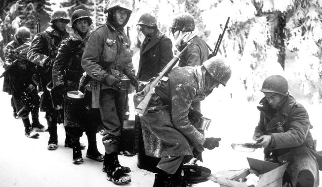 In this Jan. 13, 1945 file photo, and provided by the U.S. Army, American soldiers of the 347th U.S. Infantry wear heavy winter gear as they receive rations in La Roche, Belgium. (U.S. Army, via AP, File)