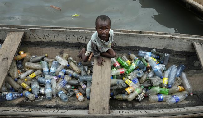 A child sits inside a canoe with empty plastic bottles he collected to sell for recycling in the floating slum of Makoko in Lagos, Nigeria, Nov. 8, 2022. Negotiators from around the world gather at UNESCO in Paris on Monday, May 29, 2023, for a second round of talks aiming toward a global treaty on fighting plastic pollution in 2024. (AP Photo/Sunday Alamba, File)