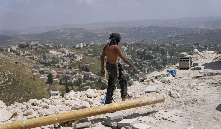 Construction continues as Jewish settlers work at a seminary that was built overnight in the West Bank outpost of Homesh, Monday, May 29, 2023. Settlers built the religious school months after Israel's far-right government repealed a 2005 act that had dismantled the outpost. (AP Photo/Ohad Zwigenberg)