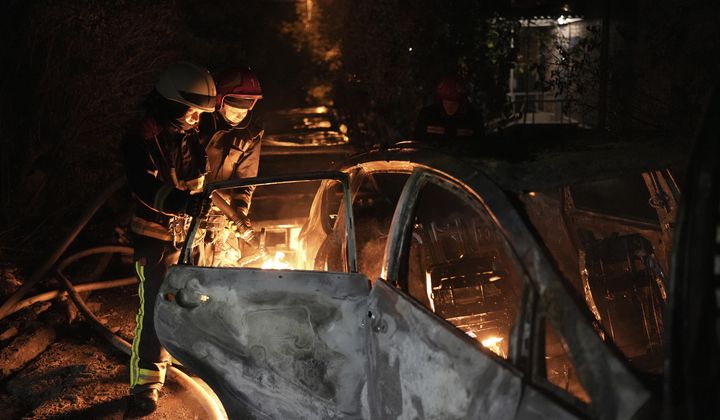 Emergency workers extinguish a fire in a parked car, caused by falling debris from the latest aerial Russian attack in the Pecherskyi district of Kyiv, Ukraine, Tuesday, May 30, 2023. (AP Photo/Roman Hrytsyna)