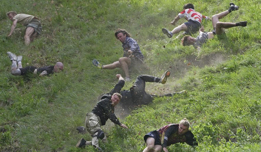 Participants compete in the men's downhill race during the Cheese Rolling contest at Cooper's Hill in Brockworth, Gloucestershire, Monday May 29, 2023. The Cooper's Hill Cheese-Rolling and Wake is an annual event where participants race down the 200-yard (180 m) long hill chasing a wheel of double gloucester cheese. (AP Photo/Kin Cheung)