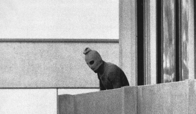 A member of the Arab commando group which seized members of the Israeli Olympic Team at their quarters appears with a hood over his face on the balcony of the village building where the commandos held members of the Israeli team hostage, at the Munich Olympic Village, on Sept. 5, 1972. A panel of historians set up to review the 1972 attack on the Munich Olympics is starting its three-year mission to reappraise what happened before, during and after the events of five decades ago on Tuesday, the German government said. (AP Photo/Kurt Strumpf, File)