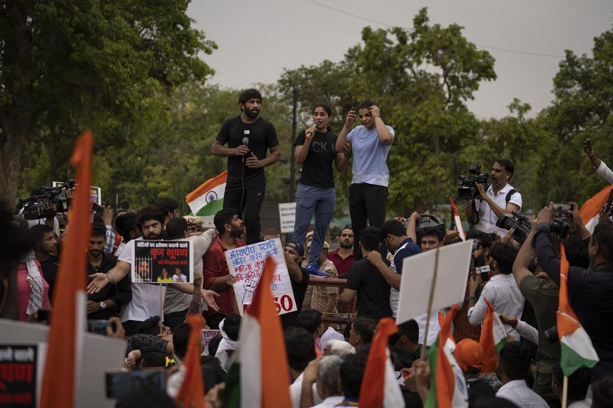 FILE- Indian wrestlers, from left, Bajrang Punia, Vinesh Phogat, and Sakshi Malik stand on a police barricade during a protest march against Brij Bhushan Sharan Singh, the president of the Wrestling Federation of India, in New Delhi, India, Tuesday, May, 23, 2023. India's top wrestlers held off from throwing their medals into the country's sacred Ganges River on Tuesday as part of an ongoing protest against sexual harassment after community leaders intervened and persuaded them against doing so. (AP Photo/Altaf Qadri, File)