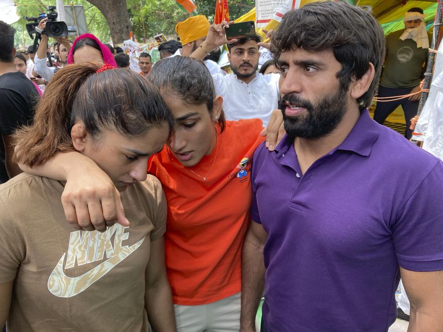 Indian wrestlers, from right, Bajrang Punia, Sangita Phogat and Vinesh Phogat talk to each other ahead of their protest march towards the newly inaugurated parliament, in New Delhi, India, Sunday, May, 28, 2023. India’s top wrestlers have been protesting for more than a month, demanding the resignation and arrest of the president of the wrestling federation for allegedly sexually harassing young athletes.(AP Photo/Shonal Ganguly)
