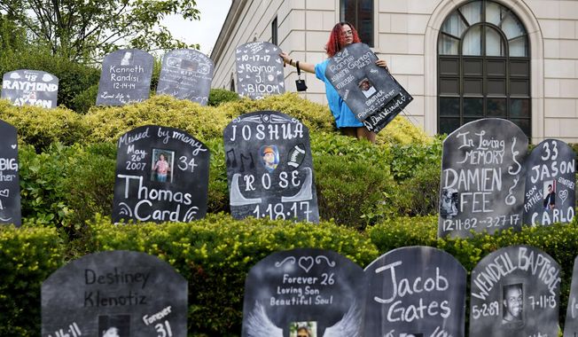 Jayde Newton helps to set up cardboard gravestones with the names of victims of opioid abuse outside the courthouse where the Purdue Pharma bankruptcy is taking place in White Plains, N.Y., on Aug. 9, 2021. A three-judge panel of the 2nd U.S. Circuit Court of Appeals in New York on Tuesday, May 30, overturned a lower court’s 2021 ruling that found bankruptcy courts did not have the authority to protect members of the Sackler family who own the company and who have not filed for bankruptcy protection from lawsuits. (AP Photo/Seth Wenig, File)