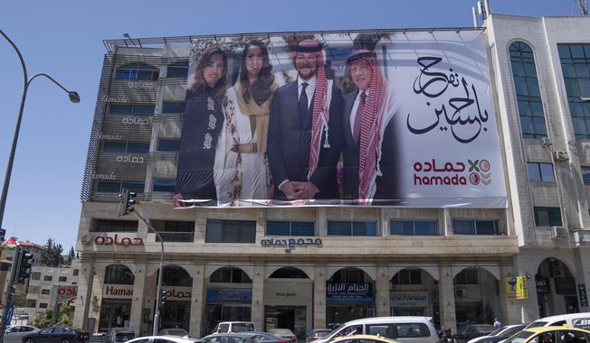 A poster with pictures of, from right, King Abdullah II, Crown Prince Hussein, Saudi architect Rajwa Alseif and Queen Rania, is hanged at the front of a building in the capital Amman, Jordan, Wednesday, May 31, 2023. Crown Prince Hussein and Saudi architect Rajwa Alseif are to be married on Thursday at a palace wedding in Jordan, a Western-allied monarchy that has been a bastion of stability for decades as Middle East turmoil has lapped at its borders. (AP Photo/Nasser Nasser)