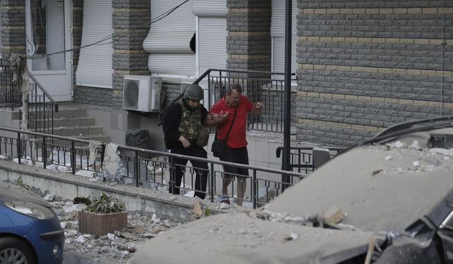A police officer helps an injured man evacuate to an ambulance from a multi-story apartment building which was damaged in a relentless wave of bombardments targeting in Kyiv, Ukraine, Tuesday, May 30, 2023. (AP Photo/Alex Babenko)