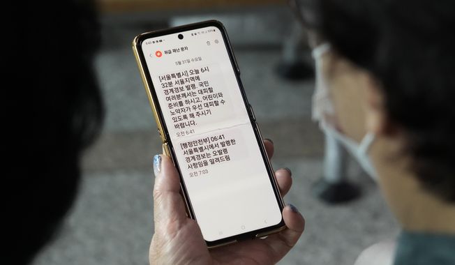 A woman looks at her mobile phone with an emergency evacuation warning text message sent to Seoul residents as she watches a news program at the Seoul Railway Station in Seoul, South Korea, Wednesday, May 31, 2023. North Korea&#x27;s attempt to put the country&#x27;s first spy satellite into space failed Wednesday in a setback to leader Kim Jong Un&#x27;s push to boost his military capabilities as tensions with the United States and South Korea rise. (AP Photo/Ahn Young-joon)