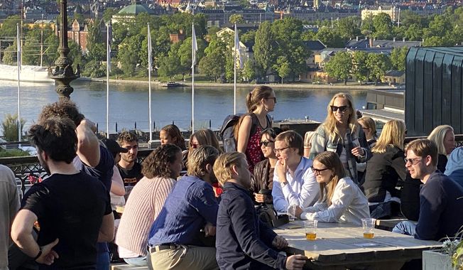 People enjoy drinks and snacks in the evening sun on a terrace overlooking Stockholm, on Tuesday, May 30, 2023. Smoking is prohibited in both indoor and outdoor areas of bars and restaurants in Sweden, which has the lowest share of smokers in the European Union. (AP Photo/Karl Ritter)