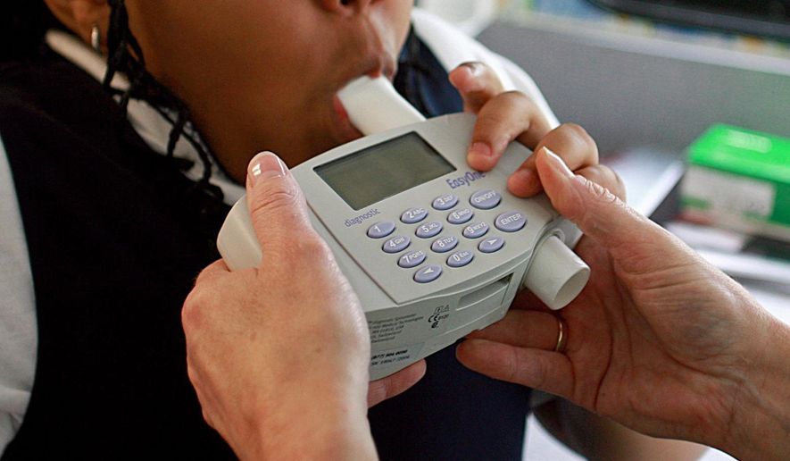 An 8-year-old student blows into a spirometer held by a nurse outside an elementary school in Bel Nor, Mo., in May 2009. Racial bias built into a common medical test for lung function is likely leading to fewer Black patients getting care for breathing problems, researchers said in a study published in JAMA Network Open on Thursday, June 1, 2023. (Christian Gooden/St. Louis Post-Dispatch via AP) **FILE**