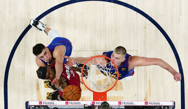 Miami Heat forward Jimmy Butler (22) shoots while defended by Denver Nuggets forward Michael Porter Jr., left, and center Nikola Jokic, right, during the second half of Game 1 of basketball&#x27;s NBA Finals, Thursday, June 1, 2023, in Denver. (AP Photo/Jack Dempsey, Pool)
