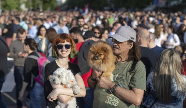 Two people carry their dogs as they attend a protest in Belgrade, Serbia, Saturday, June 3, 2023. Tens of thousands of people rallied in Serbia&#x27;s capital on Saturday in protest of the government&#x27;s handling of a crisis after two mass shootings in the Balkan country. (AP Photo/Marko Drobnjakovic)