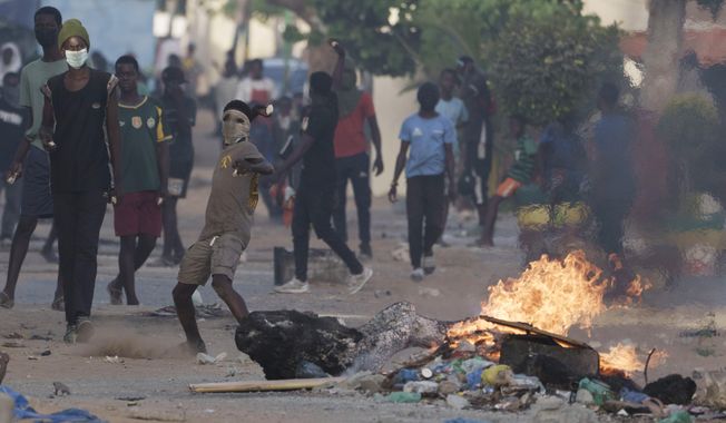 A demonstrator throws a rock at police during a protest at a neighborhood in Dakar, Senegal, Saturday, June 3, 2023. The clashes first broke out later this week after opposition leader Ousmane Sonko was convicted of corrupting youth and sentenced to two years in prison. (AP Photo/Leo Correa)