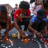 Branden Colvin Jr., center, lights candles for his father, Branden Colvin Sr., with Devina Henderson, left, and Malia Rush, right, during a candlelight vigil for Colvin, Ryan Hitchcock and Daniel Prien, at the site of a building collapse, Sunday, June 4, 2023, in Davenport, Iowa. The three men had been missing since the partial collapse of the apartment building on May 28. Colvin has since been confirmed to have died in the collapse. (Nikos Frazier/Quad City Times via AP)
