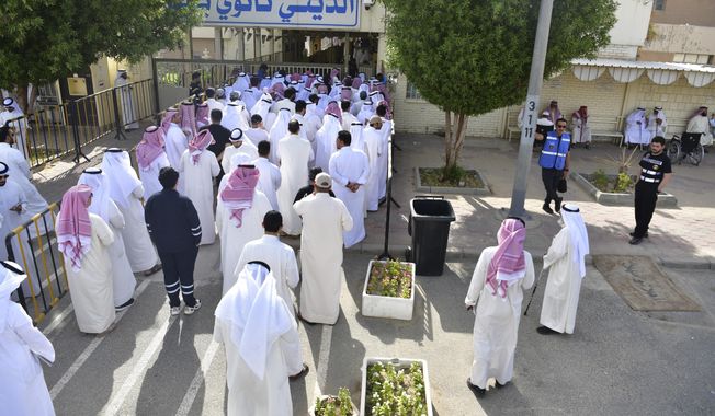 People stand in line to cast their votes in National Assembly elections at a religious school in Sabahiya district, Kuwait, Tuesday, June 6, 2022. Voters in Kuwait were casting ballots on Tuesday for a third time in as many years, with little hope of ending a prolonged gridlock between the ruling family and assertive lawmakers after the judiciary dissolved the legislature earlier this year. (AP Photo/Jaber Abdulkhaleg)
