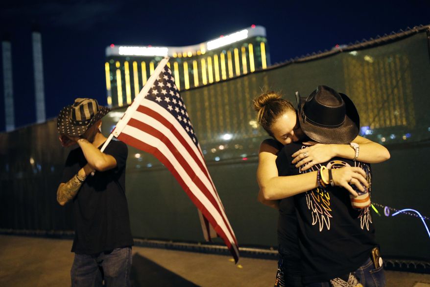 FILE - Megan Murphy, at right in hat, embraces Cara Knoedler as Kenneth Wright wipes his eyes on the first anniversary of the mass shooting, Monday, Oct. 1, 2018, in Las Vegas. Behind them is the site of the shooting. The Vegas Golden Knights and Florida Panthers didn't have much of a joint history on the ice before meeting in the Stanley Cup Final — just 10 regular season games before the series opened Saturday. But off the ice, the teams were connected by tragedy just over five years ago. (AP Photo/John Locher, File)