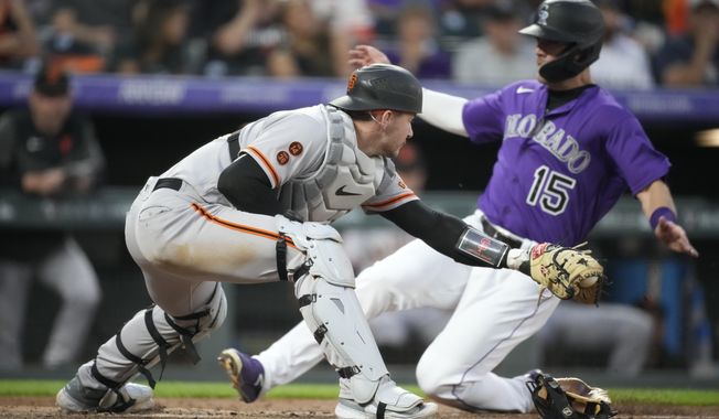 San Francisco Giants catcher Patrick Bailey, front, fields the throw as Colorado Rockies&#x27; Randal Grichuk scores from third base on a ground ball hit by Nolan Jones in the fourth inning of a baseball game Tuesday, June 6, 2023, in Denver. (AP Photo/David Zalubowski)
