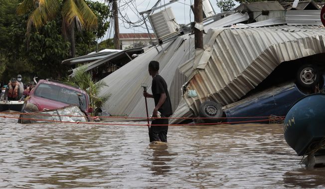 In this Nov. 6, 2020, file photo, a resident walking through a flooded street looks back at storm damage caused by Hurricane Eta in Planeta, Honduras. Environmental campaigners called Wednesday for fossil fuel producers to contribute to a new fund intended to help poor countries cope with climate disasters. (AP Photo/Delmer Martinez, File)
