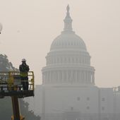 Workers finish tending a street lamp as smoke from Canadian wildfires obscures the view of the U.S. Capitol Building in Washington, Thursday, June 8, 2023. The haze from the wildfires is taking its toll on outdoor workers along the Eastern U.S. who carried on with their jobs even as dystopian orange skies forced the cancelation of sports events, school field trips and Broadway plays.  (AP Photo/Susan Walsh)