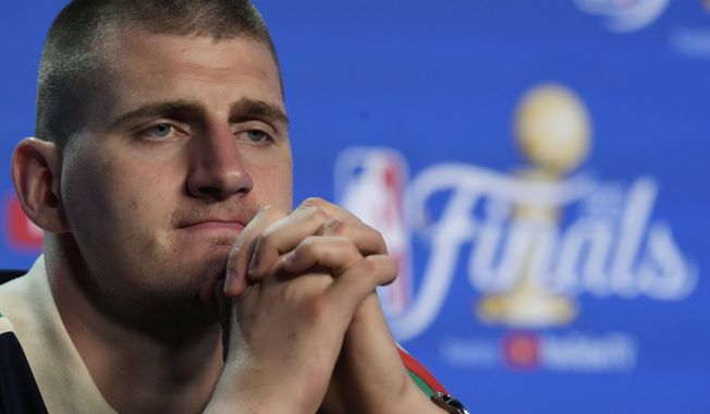 Denver Nuggets center Nikola Jokic (15) listens to a question during a post game news conference after Game 3 of the NBA Finals basketball game against the Miami Heat, Thursday, June 8, 2023, in Miami. (AP Photo/Rebecca Blackwell)