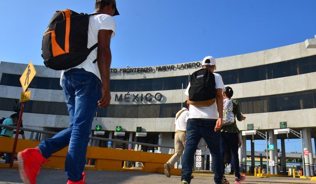 U.S. asylum-seekers being returned by U.S. authorities under the so-called Remain in Mexico program are escorted by a Mexican migration agent as they walk back into Nuevo, Laredo Mexico, across the international bridge from Laredo, Texas, Wednesday, July 10, 2019. The Biden administration has stopped taking appointments via its mobile phone app from asylum seekers in a notoriously dangerous and corrupt Mexican border city amid signs migrants who used it were being targeted for extortion. (AP Photo/Salvador Gonzalez) **FILE**