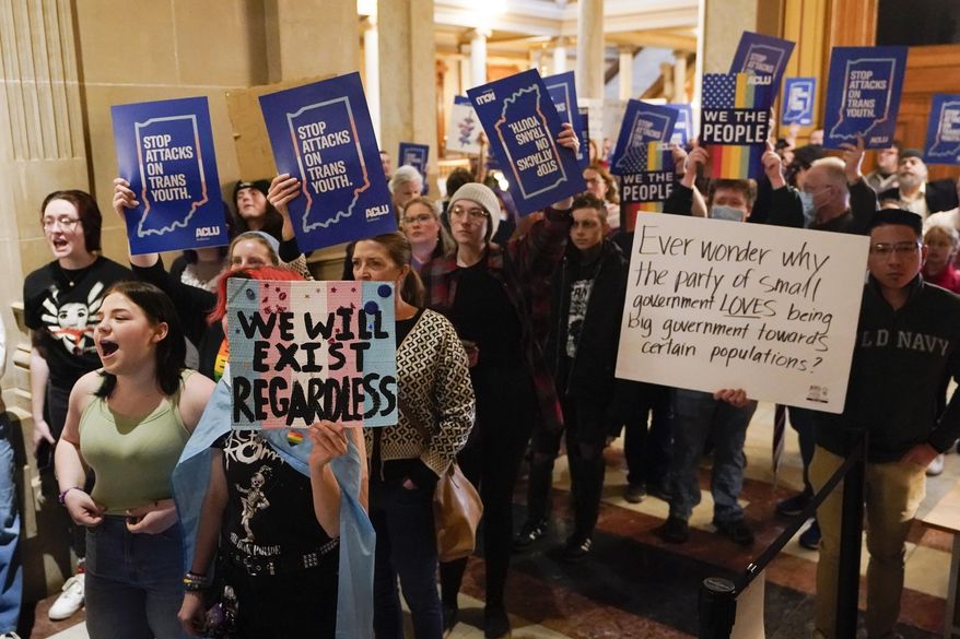 Protesters stand outside of the Senate chamber at the Indiana Statehouse on Feb. 22, 2023, in Indianapolis. A federal judge is scheduled Wednesday, June 14, to hear arguments in a lawsuit seeking to block an Indiana law banning doctors from providing puberty blockers, hormones and gender-affirming surgeries to minors. (AP Photo/Darron Cummings, File)