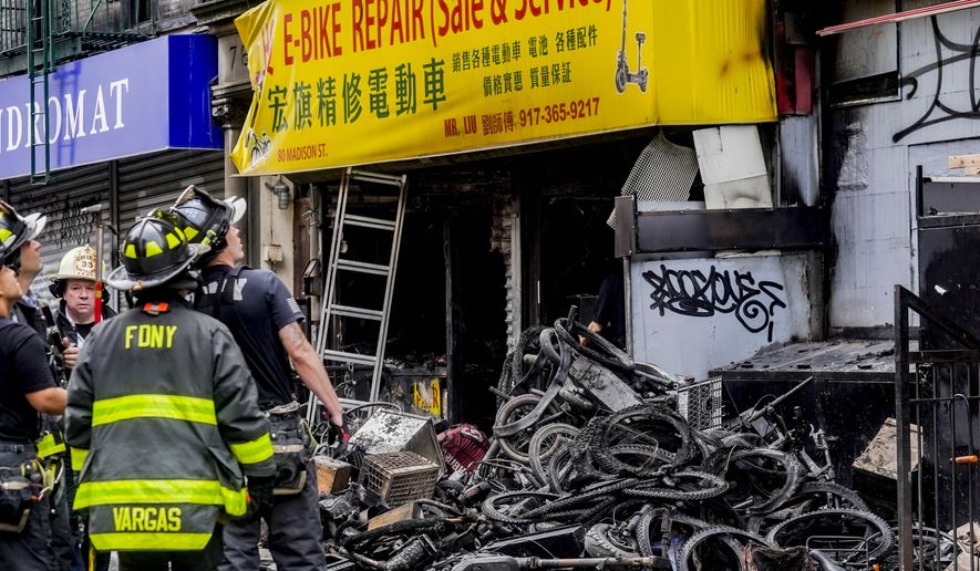 Firefighters and investigators go through the aftermath of a fire which authorities say started at an e-bike shop and spread to upper-floor apartments, Tuesday, June 20, 2023, in New York. (AP Photo/Bebeto Matthews)