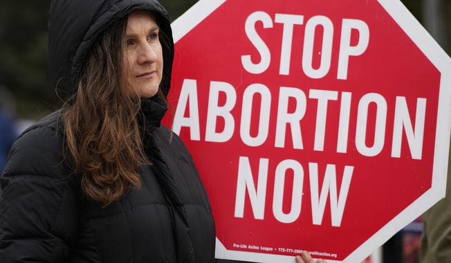 Kinga Gebauer holds a sign in front of the Walgreens corporate headquarters during a protest over plan to sell abortion pills at Walgreens Deerfield Headquarters in Deerfield, Ill., Tuesday, Feb. 14, 2023. One year ago, the U.S. Supreme Court rescinded a five-decade-old right to abortion, prompting a seismic shift in debates about politics, values, freedom and fairness. (AP Photo/Nam Y. Huh) **FILE**