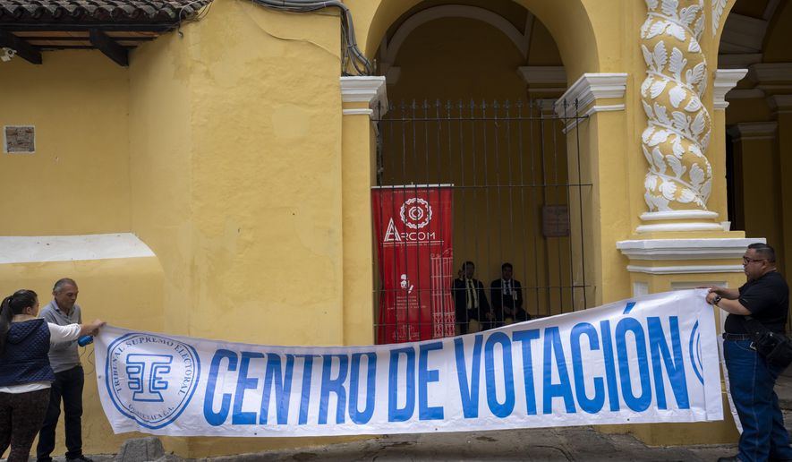 Volunteers hang a banner with a message that reads in Spanish; "voting center," on the facade of a polling station, in Antigua, Guatemala, Saturday, June 24, 2023. Guatemalans go to the polls to elect a new president on June 25. (AP Photo/Moises Castillo)
