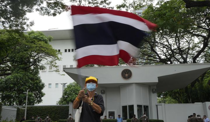 A Royalist protester waves a Thai national flag in front of the U.S. Embassy in Bangkok, Thailand, on May 24, 2023. The U.S. ambassador to Thailand dismissed claims of American interference in recent elections as a &quot;disservice&quot; to the Thai people, saying Tuesday, June 27, 2023, that Washington does not support any individual candidate or political party. (AP Photo/Sakchai Lalit)
