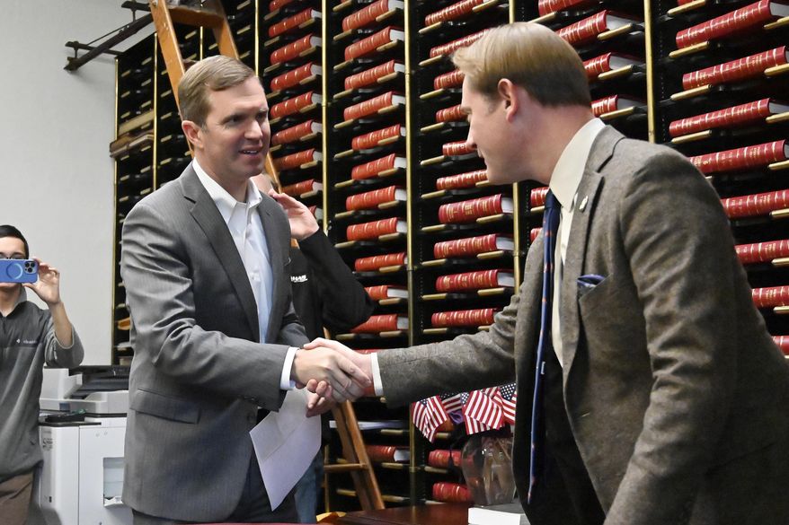 FILE - Kentucky Gov. Andy Beshear, left, shakes hands with Kentucky Secretary of State Michael Adams as he arrives to file the paperwork officially entering the race for re-election in Frankfort, Ky., Dec. 5, 2022. Kentucky’s Democratic governor and Republican secretary of state teamed up Thursday, June 29, to quickly implement a new state law aimed at protecting domestic violence victims from their abusers. (AP Photo/Timothy D. Easley, File)