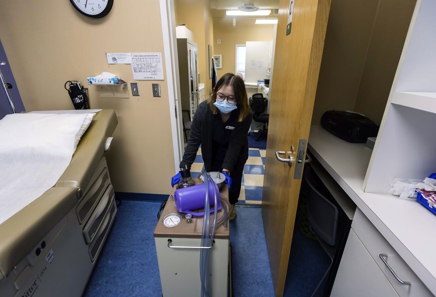 Lab assistant Sydni Hanson transports a suction machine into a patient room, Thursday, July 7, 2022, at WE Health Clinic in Duluth, Minn. Minnesota recorded a 20% jump in abortions in 2022, partly because more patients are traveling from states that have banned or limited the procedure since the U.S. Supreme Court overturned Roe v. Wade, according to an annual report released Friday, June 30, 2023. (AP Photo/Derek Montgomery) **FILE**