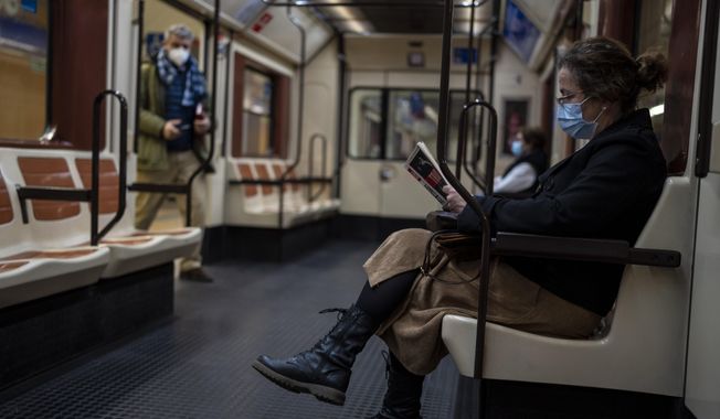 FILE - A woman wearing a face mask reads a book on a subway in Madrid, Spain, Thursday, Jan. 20, 2022. The Spanish government on Tuesday, July 4, 2023, declared an end to the health crisis caused by the COVID-19 pandemic, and says people no longer have to wear masks in health and care centers as well as pharmacies. (AP Photo/Manu Fernandez, File)